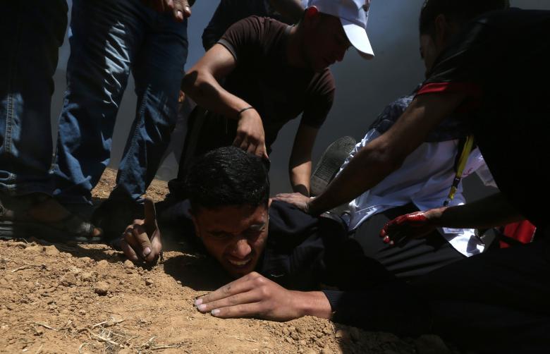 A wounded Palestinian reacts as he falls on the ground during a protest against U.S. embassy move to Jerusalem and ahead of the 70th anniversary of Nakba, at the Israel-Gaza border in the southern Gaza Strip.
