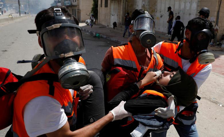 A female Palestinian medic is evacuated after inhaling tear gas fired by Israeli forces during a protest against U.S. embassy move to Jerusalem and ahead of the 70th anniversary of Nakba, at Israeli Qalandia checkpoint near Ramallah in the occupied West 