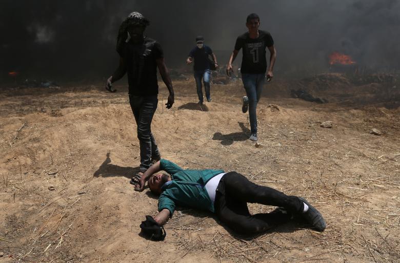 A Palestinian lies on the ground during a protest against U.S. embassy move to Jerusalem and ahead of the 70th anniversary of Nakba, at the Israel-Gaza border in the southern Gaza Strip.