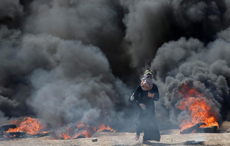 A female Palestinian demonstrator gestures during a protest against U.S. embassy move to Jerusalem and ahead of the 70th anniversary of Nakba, at the Israel-Gaza border, east of Gaza City.