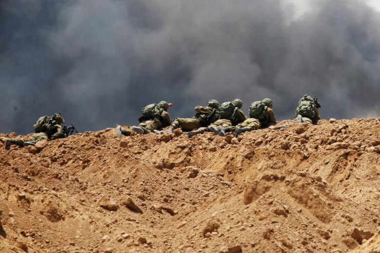 Smoke rises as Israeli soldiers are seen on the Israeli side of the border with the Gaza Strip.