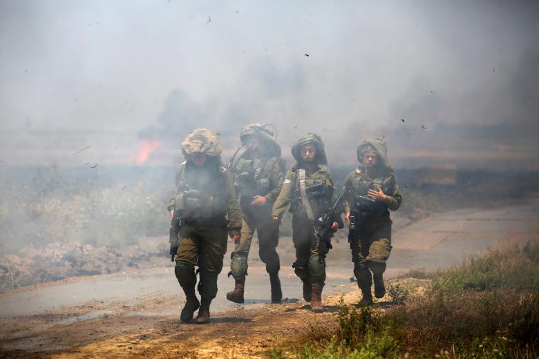 Israeli soldiers patrol near a burning field on the Israeli side of the border between Israel and Gaza, May 14, 2018.