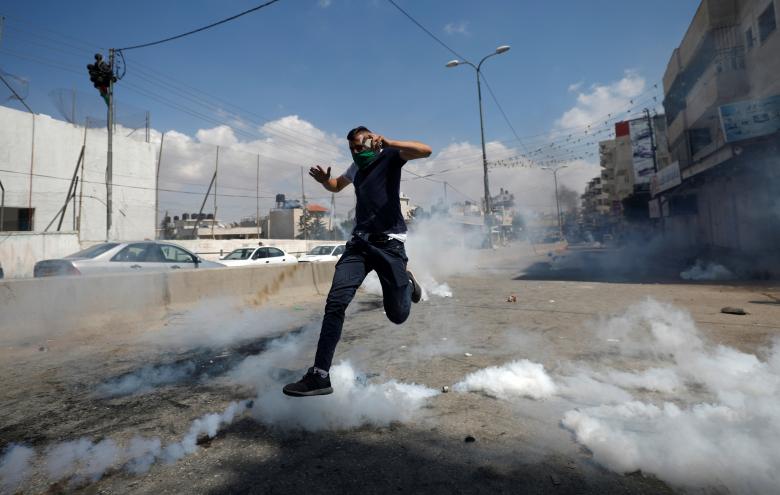 A Palestinian demonstrator runs from tear gas fired by Israeli troops during a protest against U.S. embassy move to Jerusalem and ahead of the 70th anniversary of Nakba, near Israeli Qalandia checkpoint near Ramallah in the occupied West Bank.