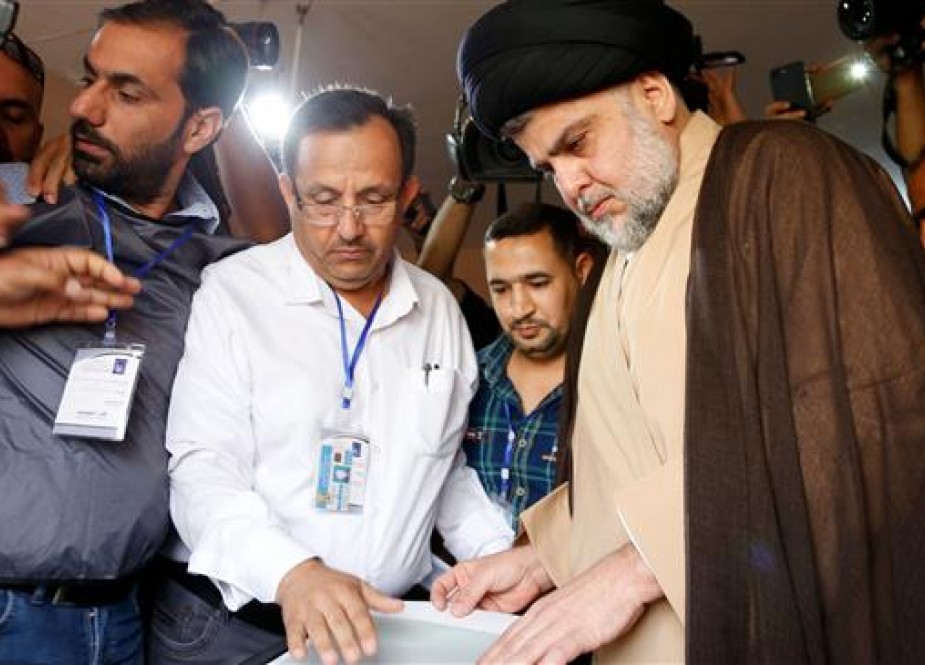 Iraqi cleric Moqtada al-Sadr (C-R) votes through an electronic counting machine at a polling station in the central holy city of Najaf on May 12, 2018. (AFP photo)