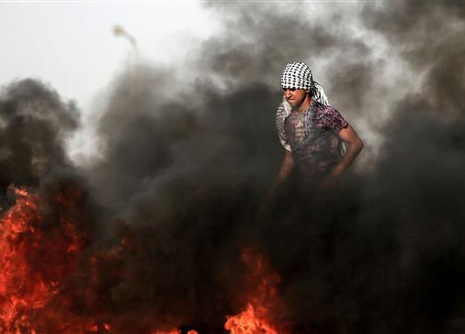 A Palestinian demonstrator walks in the smoke billowing from burning tires during clashes with Israeli forces along the border with the Gaza strip east of Gaza city on May 18, 2018. (Photo by AFP)