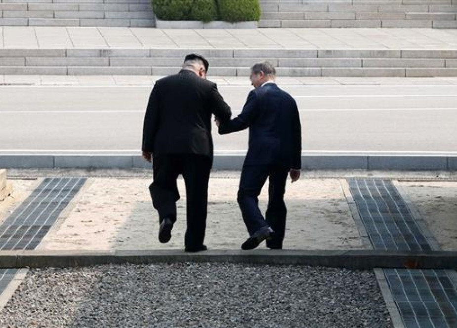 North Korea’s leader Kim Jong-un (L) takes South Korea’s President Moon Jae-in over the Military Demarcation Line that divides their countries and into North Korean territory, at Panmunjom, on April 27, 2018. The two briefly stepped over the line into the North before walking back and to the Peace House building on the southern side of the truce village of Panmunjom for a summit. (Photo by AFP)