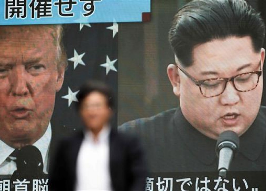 A pedestrian walks in front of a screen in Tokyo on May 25, 2018 flashing a news report relating to US President Donald Trump cancelling his meeting with North Korean leader Kim Jong Un. (Photo by AFP)