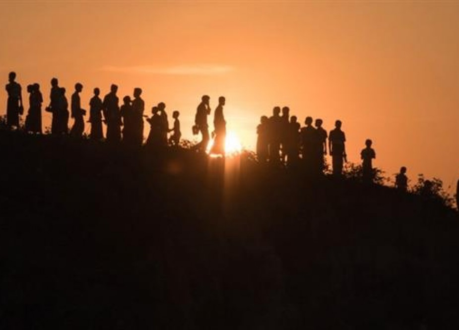 In this photo, taken on November 26, 2017, Rohingya Muslim refugees are seen walking down a hillside in the Kutupalong refugee camp in Cox’s Bazar, Bangladesh. (By AFP)