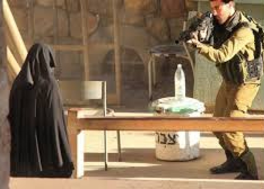 Israeli soldier pointing a gun at a Palestinian woman..jpg