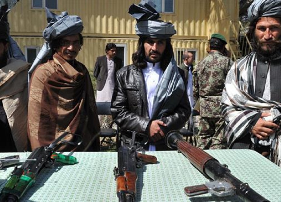Former Taliban militants look on as they stand alongside their weapons in Jalalabad, the capital of Nangarhar province on March 19, 2014. (Photo by AFP)