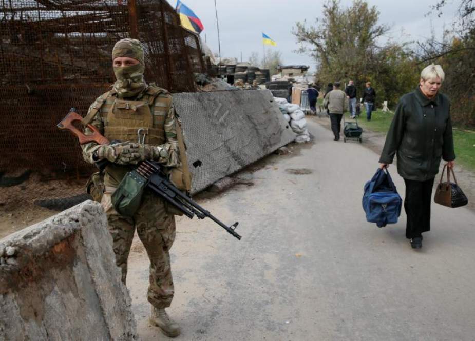 A Ukrainian soldier stands guard as residents walk through a checkpoint on the contact line between pro-Moscow rebels and Ukrainian troops in the settlement of Stanytsia Luhanska in the Luhansk region of Ukraine on October 9.
