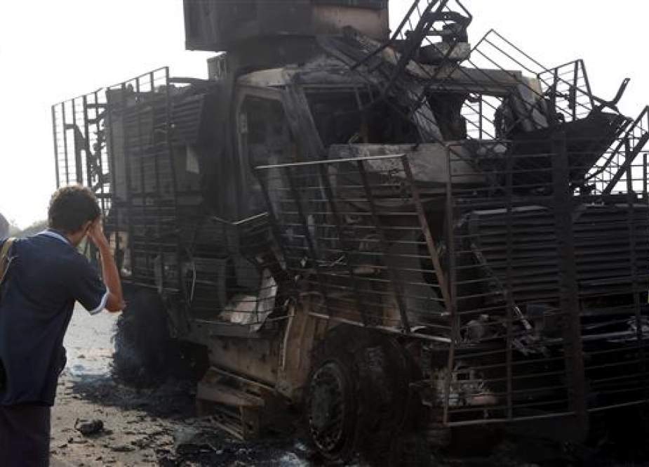 Yemenis check the wreckage of an armored vehicle