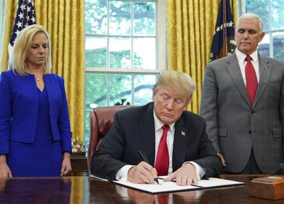Watched by Homeland Security Secretary Kirstjen Nielsen (L) and Vice President Mike Pence, US President Donald Trump signs an executive order on immigration in the Oval Office of the White House on June 20, 2018 in Washington, DC. (AFP photos)