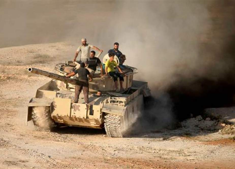 Syrian militants ride a tank in Dara