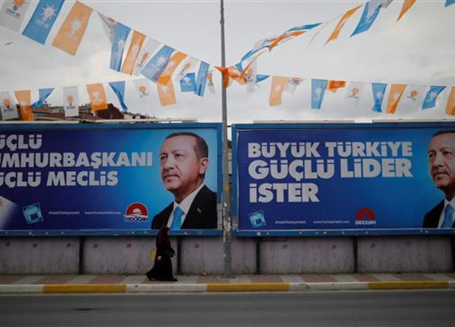 A woman passes by election posters of Turkey