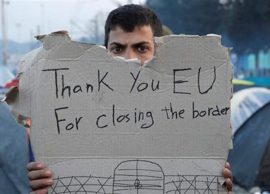 A refugee holds a message, "Thank you EU for closing the border," during a protest asking for the opening of borders at a makeshift camp at the Greek-Macedonian border on March 18, 2016. (Reuters Photo)