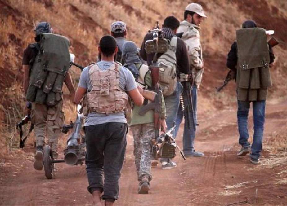 Militants walk with their arms near the frontline against Syrian government forces west of the southern city of Dara