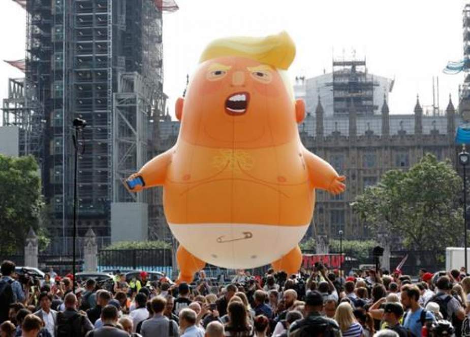 Protesters gather around a giant balloon depicting US President Donald Trump as an orange baby during a demonstration against Trump