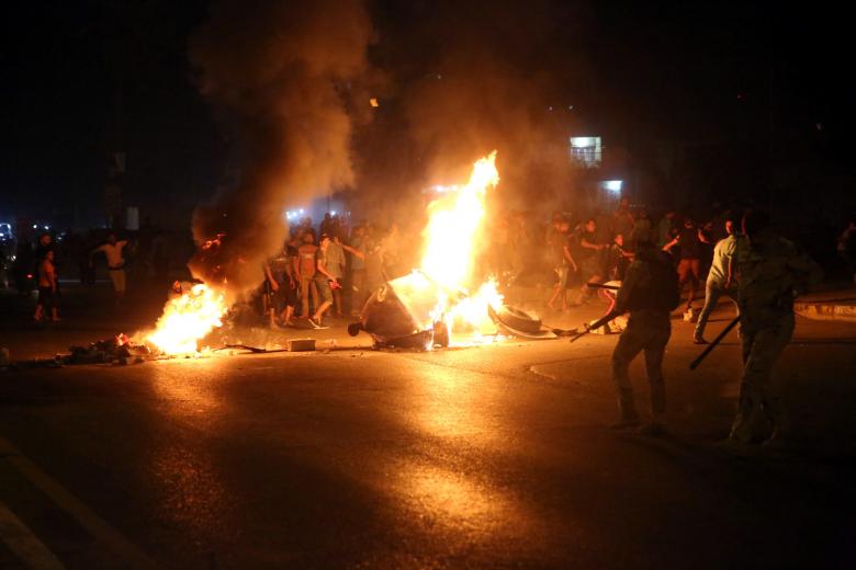 Iraqi protesters burn tyres and block the road in front of Security forces in Kerbala, July 14.
