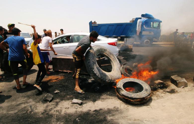 Iraqi protesters burn tires and block the road at the entrance to the city of Basra, July 12.