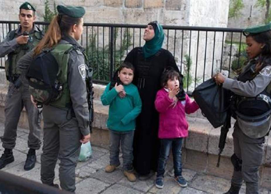 Israeli forces inspect the purse of a Palestinian woman with her children at the Damascus Gate of Jerusalem al-Quds on March 13, 2016. (Photo by AFP)
