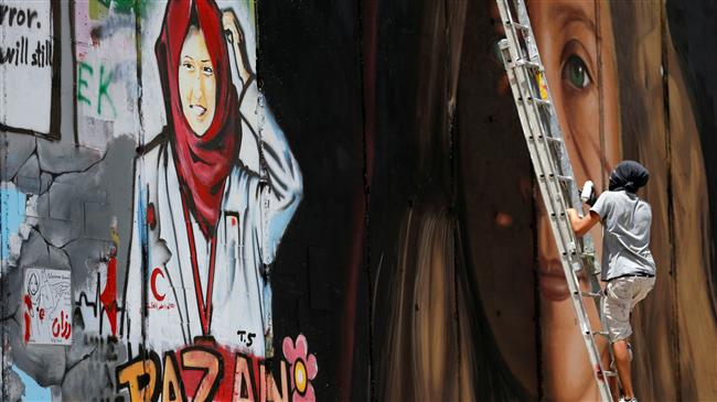 A foreign artist paints on a wall a mural depicting Palestinian teen Ahed Tamimi next to a mural of dead Palestinian nurse Razan Al-Najar, Bethlehem, the occupied West Bank, July 25, 2018.