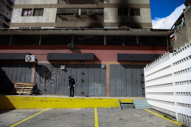 A criminal investigator looks for evidence in a building after an explosion in Caracas, August 5, 2018.