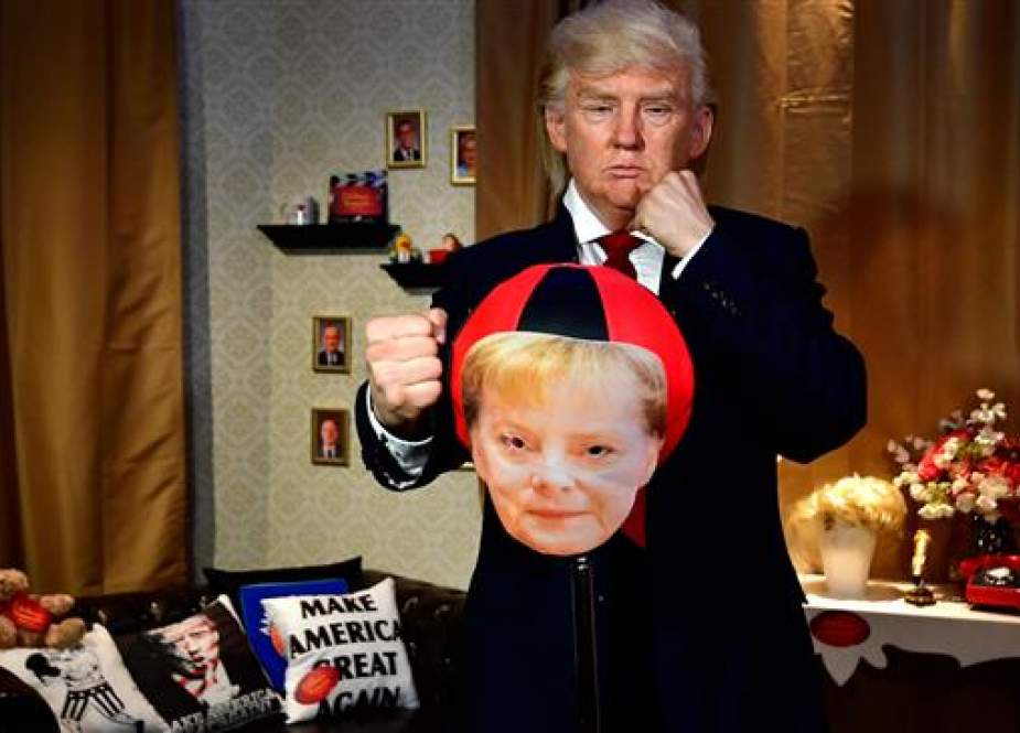 An artist wearing a silicon mask depicting US President Donald Trump boxing in a punchball with a portrait of German Chancellor Angela Merkel performs during a live performance at Madame Tussaud