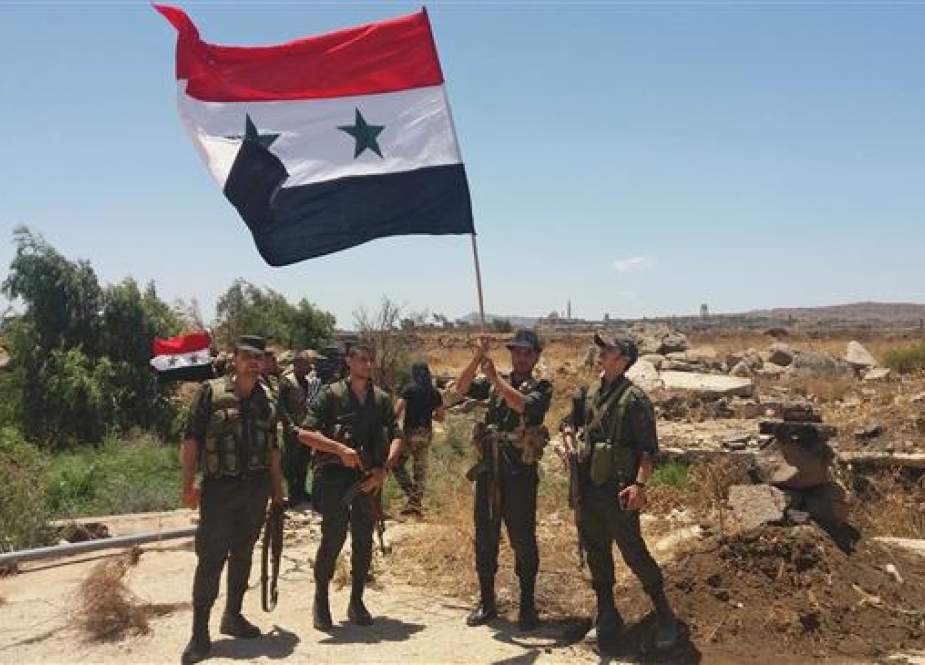 A handout picture released by the official Syrian Arab News Agency (SANA) on July 26, 2018 shows Syrian army soldiers carrying the national flag in the village of Hamidiya in the southern province of Quneitra. (Via AFP)