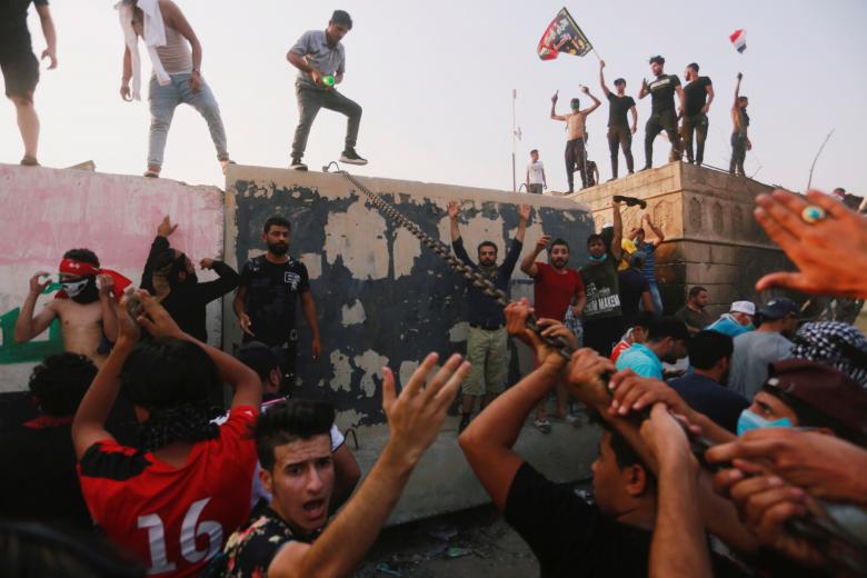 Protesters push down concrete blast walls of the government office building in Basra, September 5, 2018.