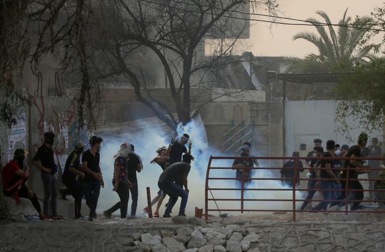 Iraqi protesters run from teargas during a protest near the building of the government office in Basra, September 5, 2018.