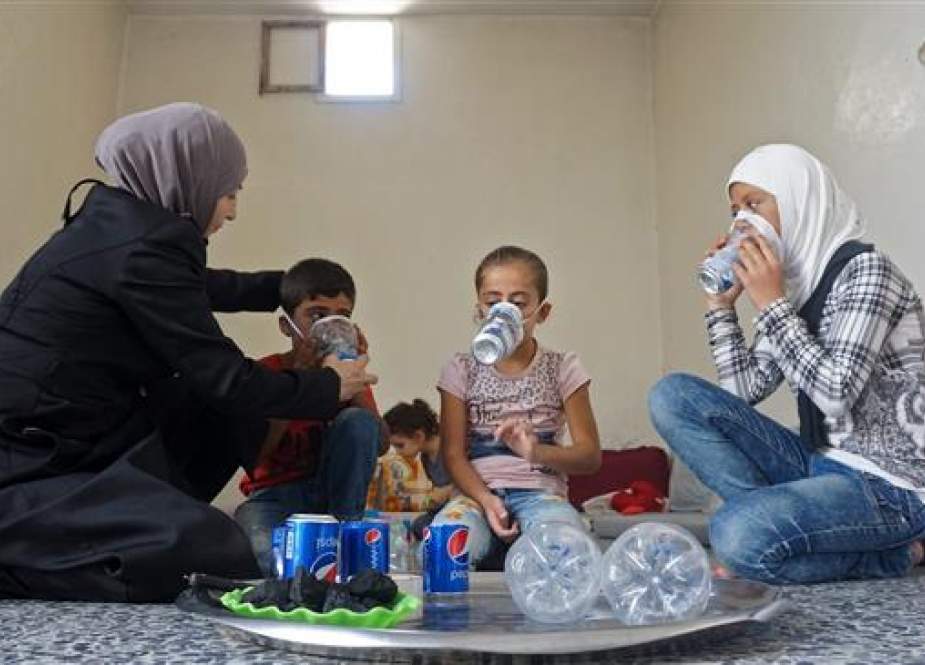 Syrian woman tries an improvised gas mask on family members in her home in Idlib Province.jpg