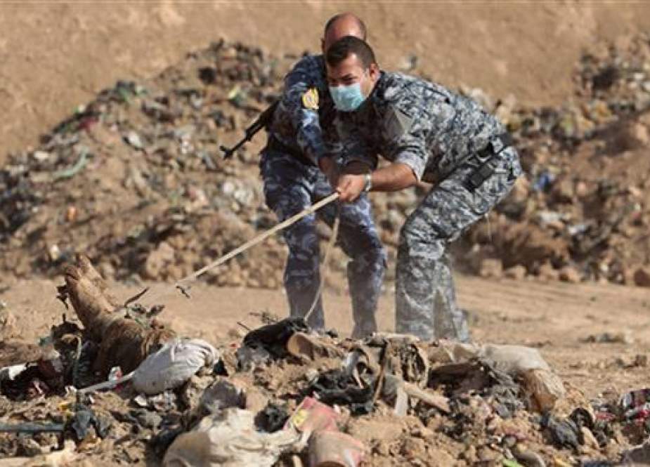 This file picture shows members of Iraqi police inspecting a mass grave containing dead bodies of people killed by the Daesh terrorist group near the northern city of Mosul. (Photo by AFP)