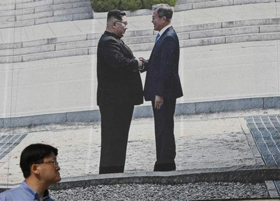 A man walks past a giant banner showing a picture of a handshake between South Korean President Moon Jae-in (R) and North Korean leader Kim Jong-un, at Seoul City Hall, Seoul, South Korea, September 13, 2018. (Photo by AFP)