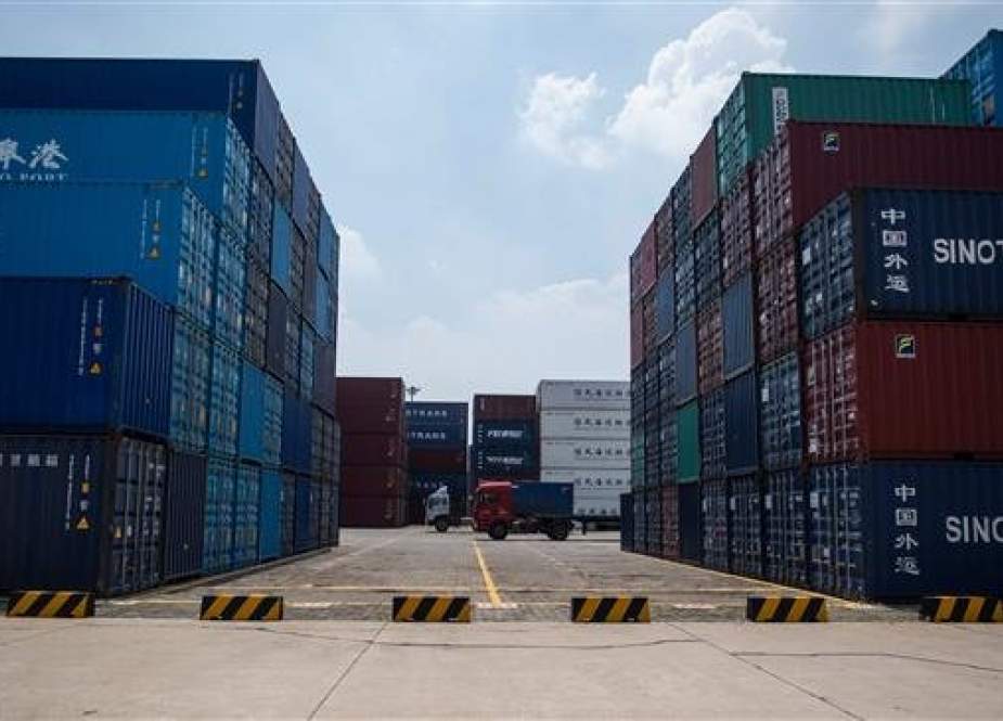 (FILES) This file picture taken on August 7, 2018 shows a truck (C) transporting a container next to stacked containers at a port in Zhangjiagang in China