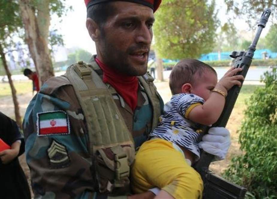 An Iranian soldier carries a child at the site of an attack on a military parade in the southwestern Iranian city of Ahvaz on September 22, 2018. (Photo by Mehr News Agency)
