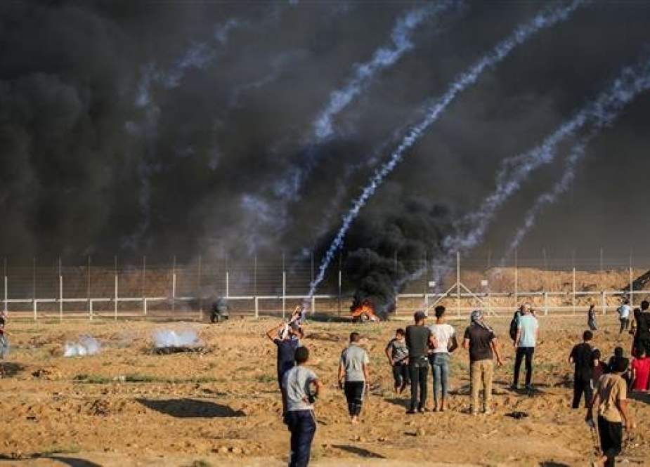 Palestinian protesters stand by as tear gas canisters fired by Israeli forces fall amidst them in clashes during a demonstration along the Israeli fence east of Gaza City on September 21, 2018. (AFP)