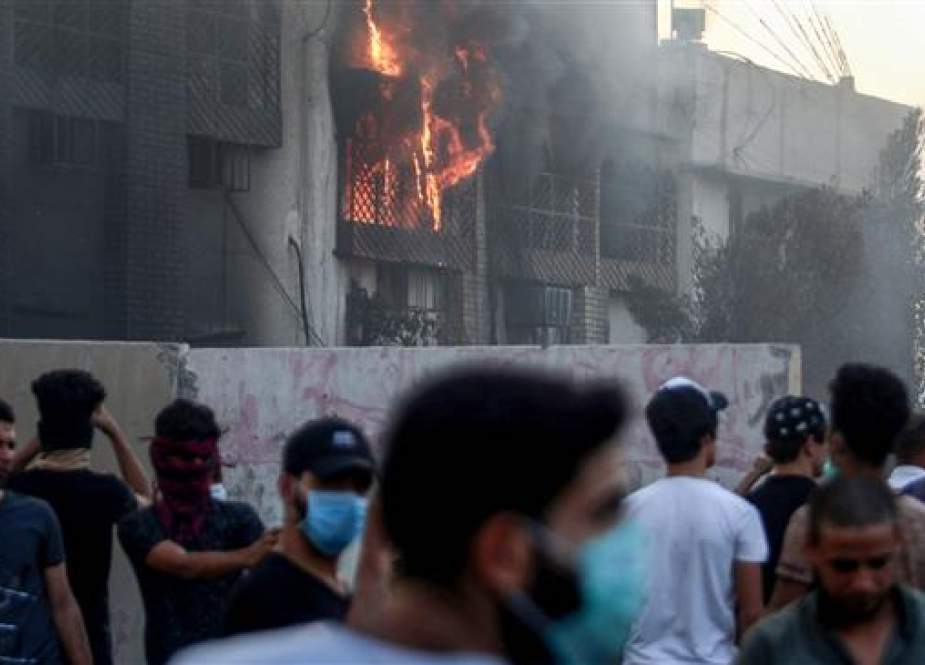 Iraqi protesters gather outside the burnt-down local government headquarters in the southern city of Basra.jpg