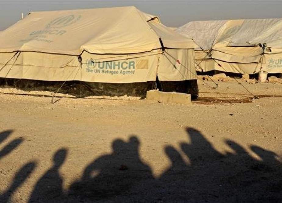 The file photo shows shadows of displaced Syrians on the ground as they watch World Cup soccer match outside Ain Issa camp in Raqqah province on June 17, 2018. (Photo by AFP)