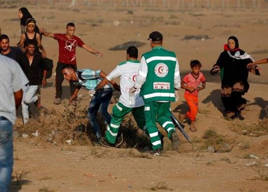 Palestinian paramedics help a protester at the border of the besieged Gaza Strip with the occupied territories, east of Gaza city, on October 12, 2018. (Photo by AFP)