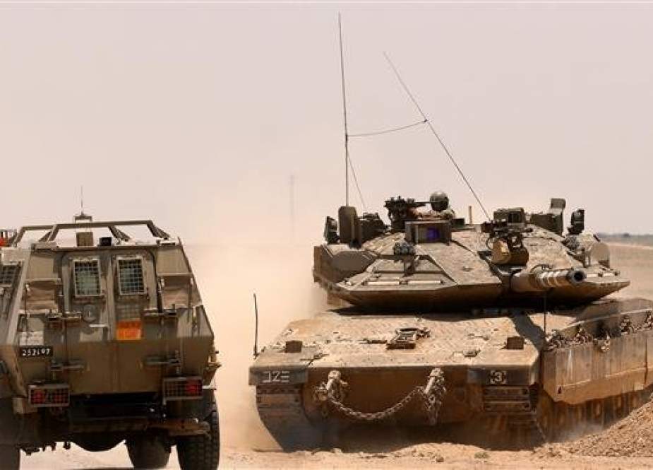 Israeli army armored vehicle driving past a Merkava Mark IV tank taking position along the Gaza fence..jpg