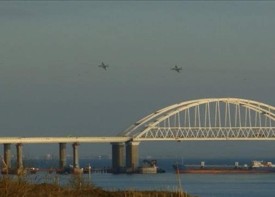 This video grab taken from footage from local media Kerch Info on November 25, 2018 shows Russian aircraft flying over the Crimean Bridge that spans the Kerch Strait, a narrow strip that links the Azov and Black seas, as a Russian ship blocks the strait. (Via AFP)