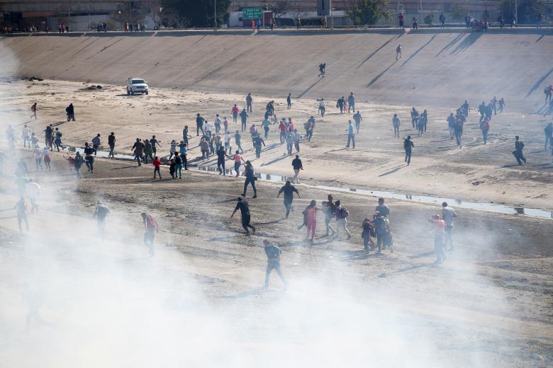 Migrants run from tear gas, thrown by the U.S. border patrol, near the border fence between Mexico and the United States in Tijuana, Mexico, November 25, 2018.