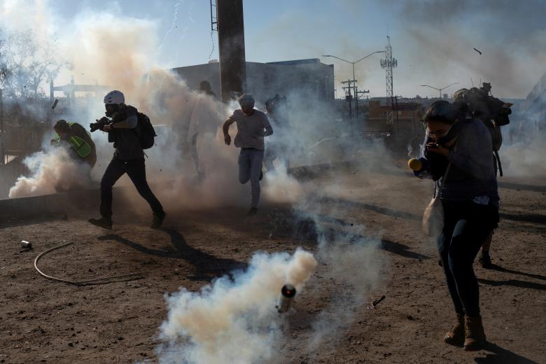 Migrants from Central America and journalists are hit by tear gas after hundreds tried to illegally cross the Mexico border into the United States in Tijuana, Mexico November 25, 2018.