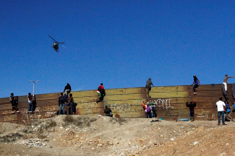 A U.S. Army helicopter patrols from the sky as migrants climb the border fence between Mexico and the United States in an attempt to cross into the U.S. side of the border in Tijuana, Mexico, November 25, 2018.