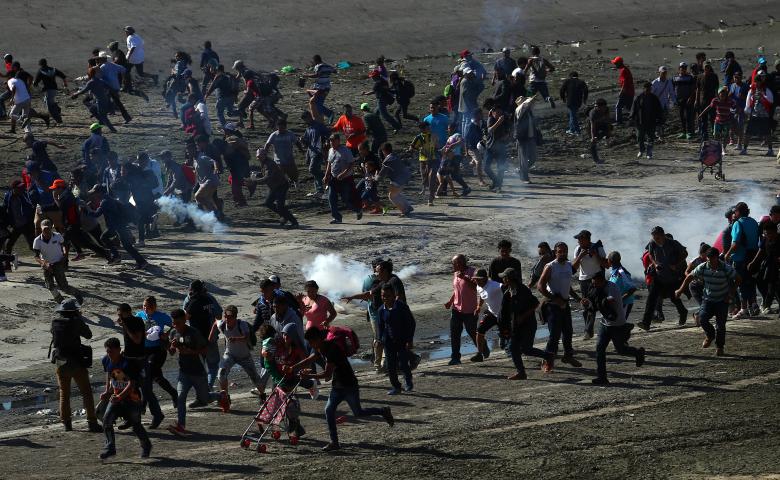 Migrants run from tear gas released by U.S. border patrol, near the border fence between Mexico and the United States in Tijuana, Mexico, November 25, 2018.