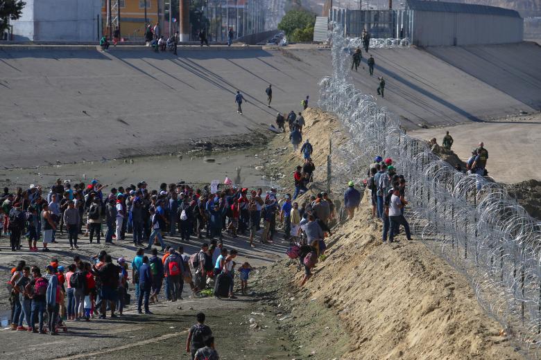Migrants stand near the border fence between Mexico and the United States as U.S. border patrol officers look on, in Tijuana, Mexico, November 25, 2018.