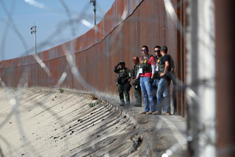 U.S. border patrol officers look at the Mexican side as they stand next to the fence between the United States and Mexico in Tijuana, Mexico November 25, 2018.