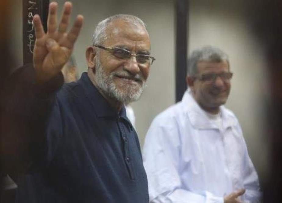 The file photo shows Muslim Brotherhood leader Mohamed Badie flashing the Rabaa sign as he stands behind bars during his trial at a court in the police academy on the outskirts of Cairo, Egypt, December 14, 2014. (Photo by Reuters)