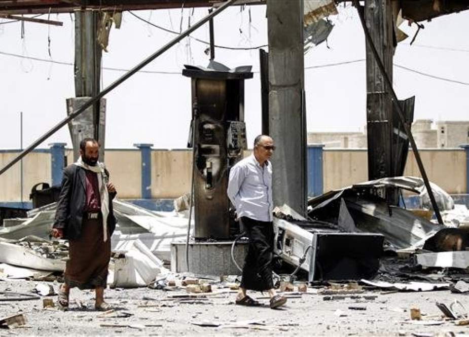 Yemeni men walk through the rubble and debris of a destroyed petrol station that was hit by a Saudi airstrike in the capital Sana’a on May 27, 2018. (By AFP)